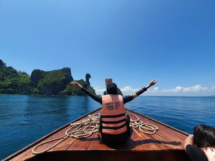 Guest in a Barracudas life jacket on the bow of a longtail boat approaching Chicken Island, Krabi