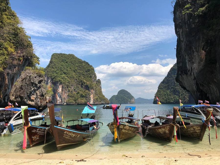 เรือหางยาวจอดเรียงรายบนหาดเกาะห้องระหว่างเขาหินปูน
