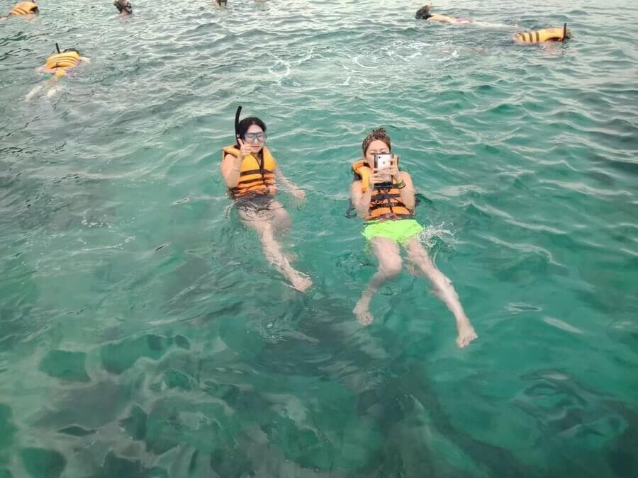 皮皮岛附近清澈海水中身穿救生衣浮潜的游客